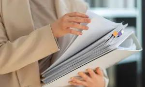 Dłonie przeglądają gruby segregator z dokumentami. To co to jest odpis dokumentu, który jest potrzebny do pracy.