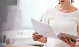 Kobieta analizuje dokumenty, być może dotyczące konsekwencji nieobecności na sprawie spadkowej.