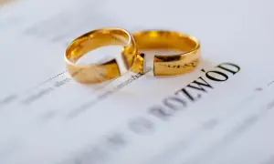Dwa złote obrączki na dokumencie z napisem "ROZWÓD".