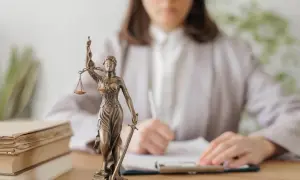 Figurka Temidy i stos książek. Czekasz na adwokata z urzędu? Czas oczekiwania bywa różny.