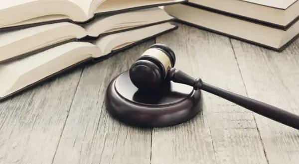 Młotek sędziowski i otwarte księgi na drewnianym stole. Ilustracja symbolizująca jak wygląda sprawa apelacyjna o alimenty.