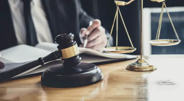 Sądowy młotek i waga sprawiedliwości na biurku. Prawnik pisze, zastanawiając się, po ilu latach przedawnia się prawo do spadku.