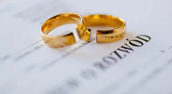 Dwa złote obrączki na dokumencie z napisem "ROZWÓD".
