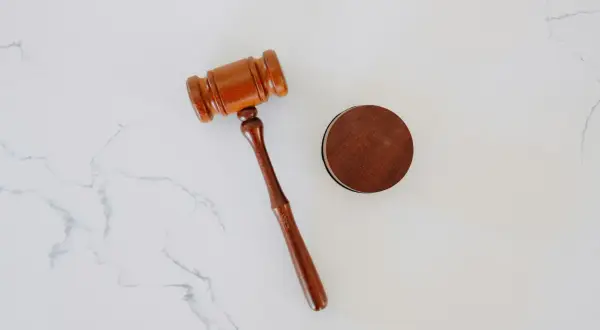 Młotek sędziowski i drewniany krążek na białym tle. Zastanawiasz się, ile trwa apelacja w sprawie karnej?