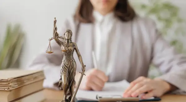 Figurka Temidy i stos książek. Czekasz na adwokata z urzędu? Czas oczekiwania bywa różny.