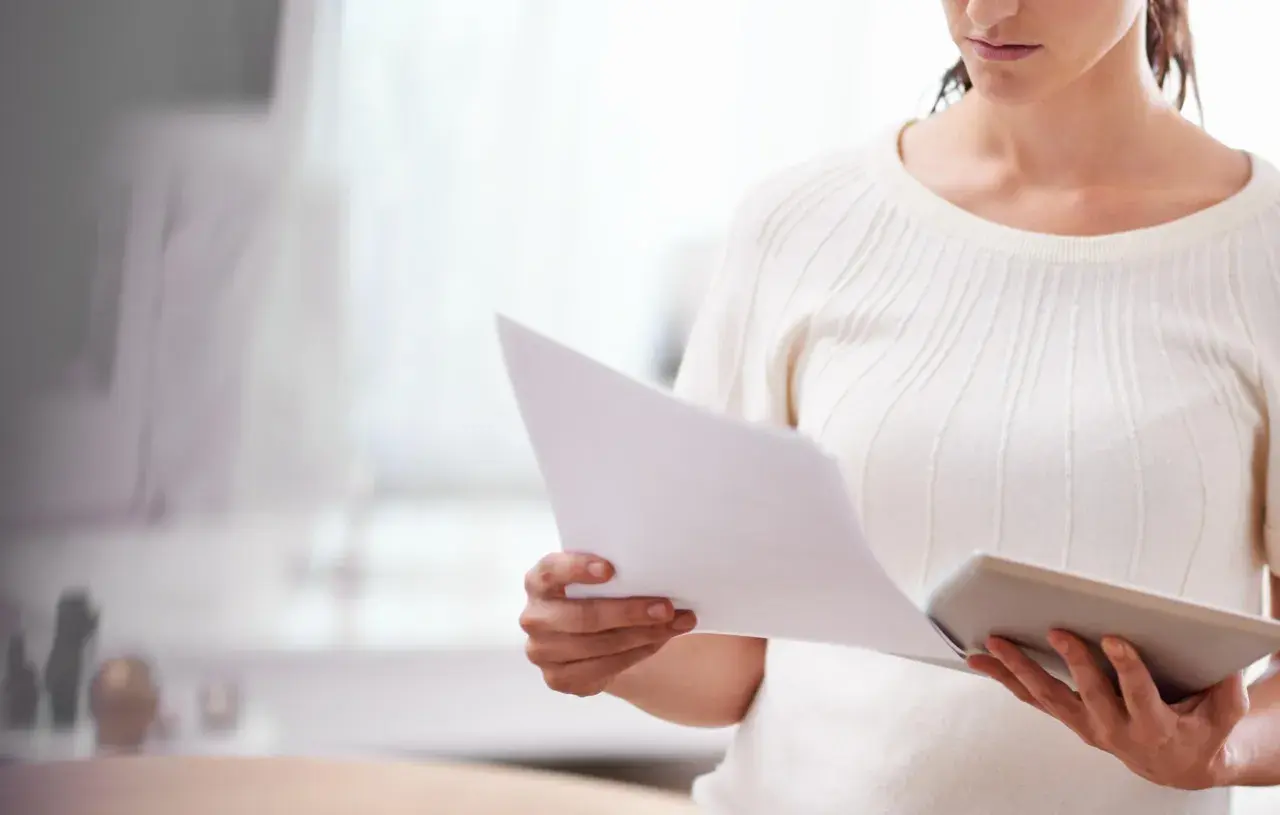 Kobieta analizuje dokumenty, być może dotyczące konsekwencji nieobecności na sprawie spadkowej.