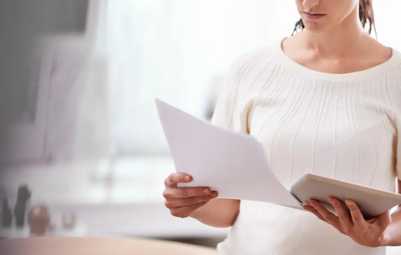 Kobieta analizuje dokumenty, przygotowując się do rozprawy o stwierdzenie nabycia spadku.